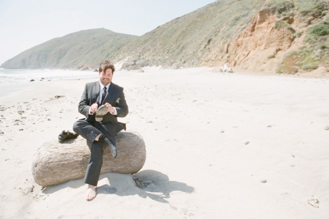 groom sitting on log at pfeiffer beach in big sur